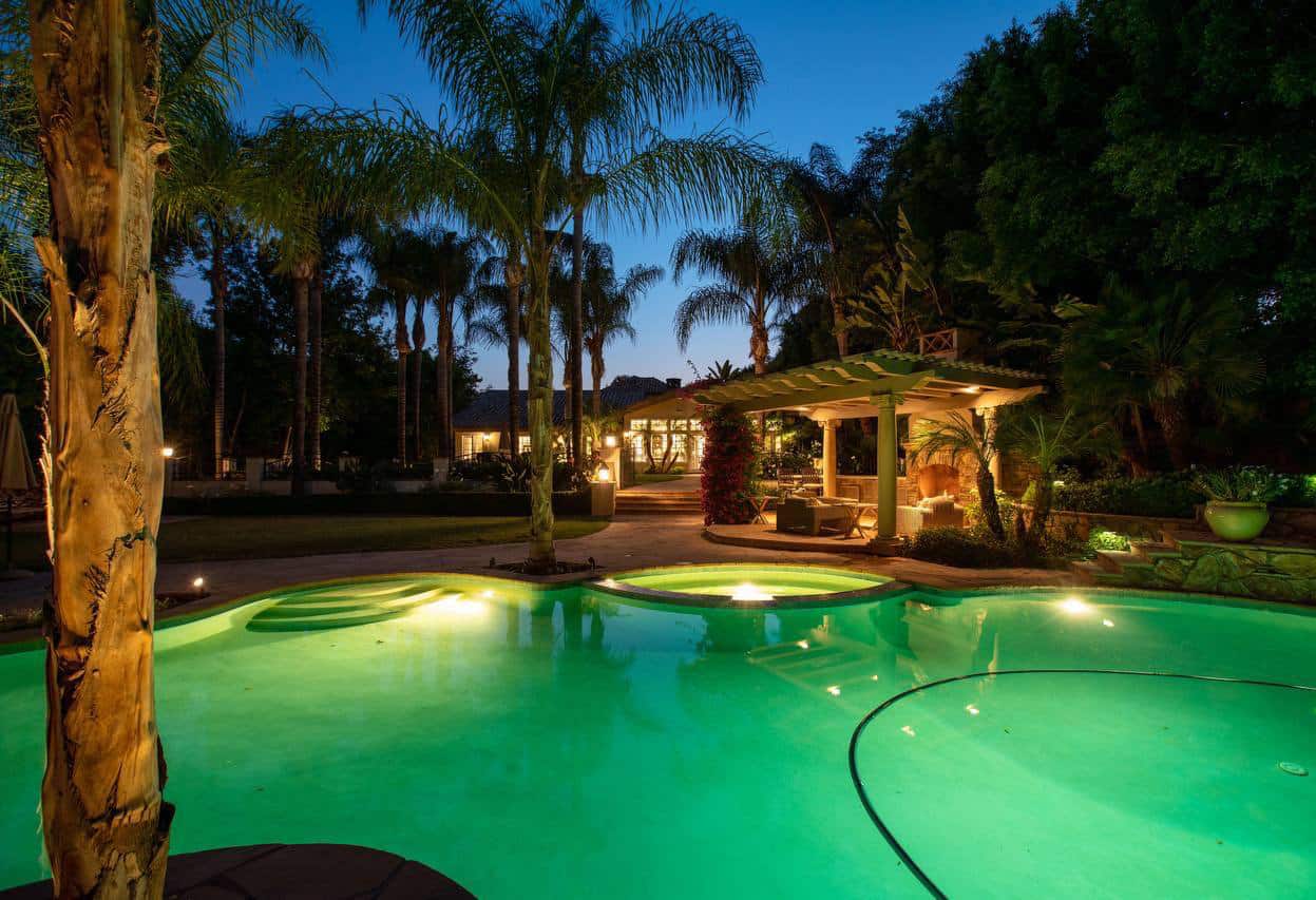 a photo of 4 seasons detox recovery center pool and backyard with covered seating and an outdoor fireplace adjacent to the pool