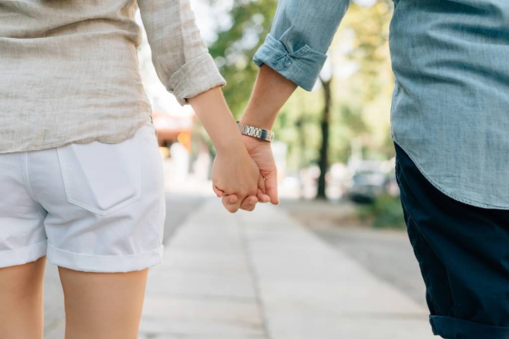 Man and woman holding hands and walking in the street